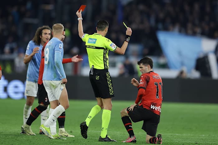 Referee Marco Di Bello pictured showing a red card to Lazio midfielder Matteo Guendouzi (left) and a yellow card to AC Milan forward Christian Pulisic (right) during a Serie A game in March 2024